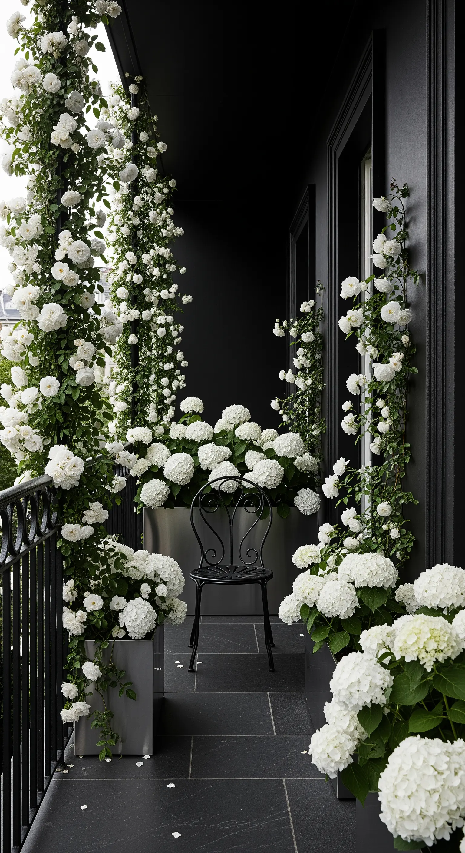 Balcone total black con vasi e pareti nere, e un'abbondanza di fiori bianchi.